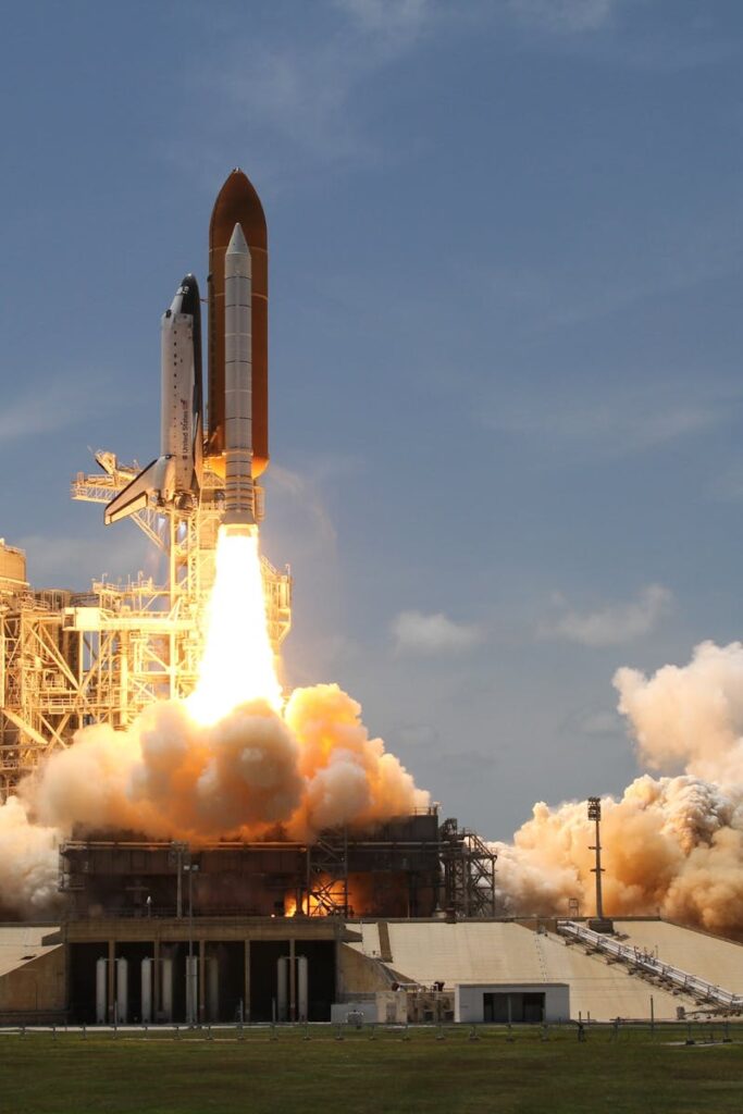 A NASA space shuttle launches with fiery liftoff, ascending into the sky amid plumes of smoke.